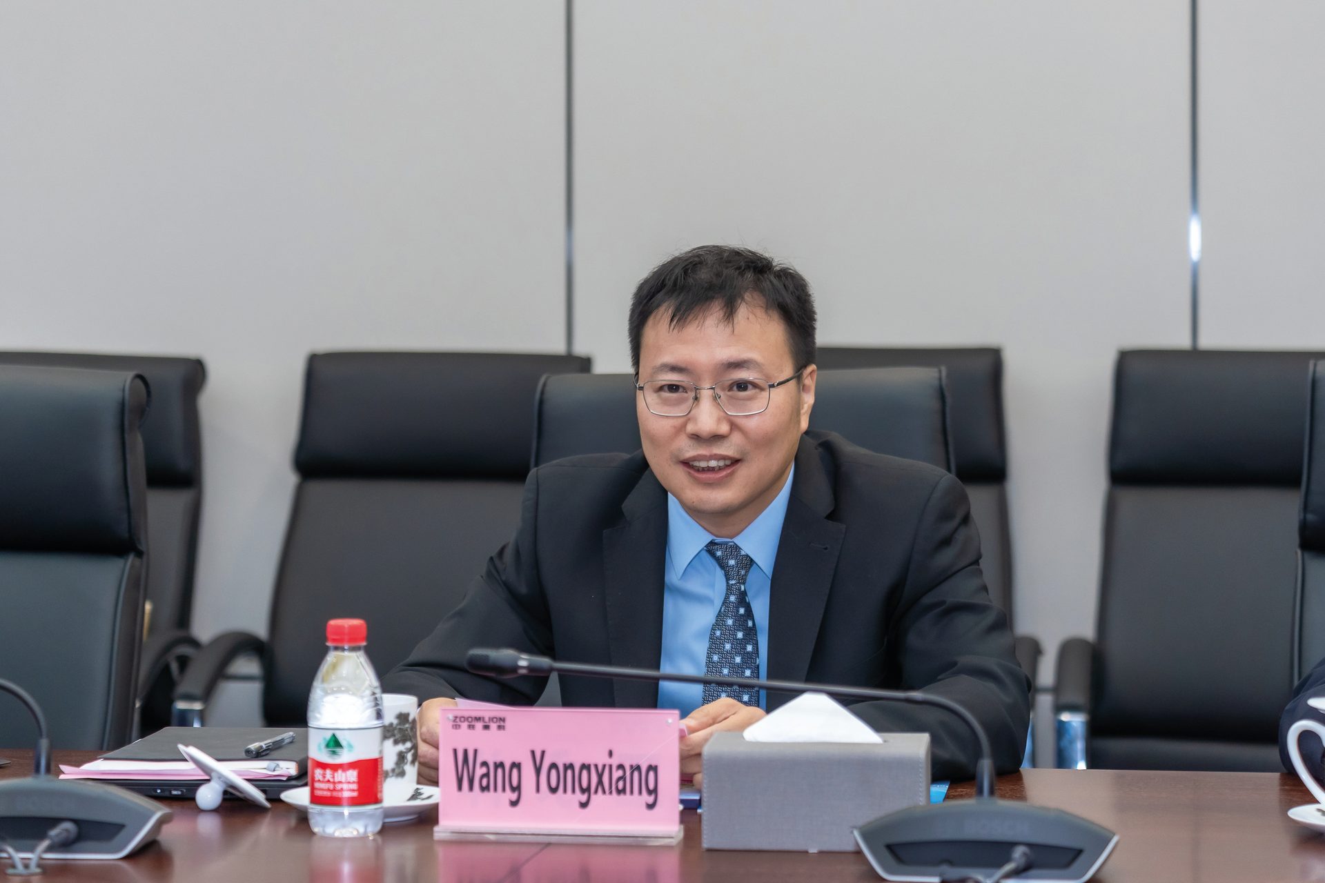 Glasses, Microphone, Table, Tableware, Bottle, Spokesperson, Tie, Suit