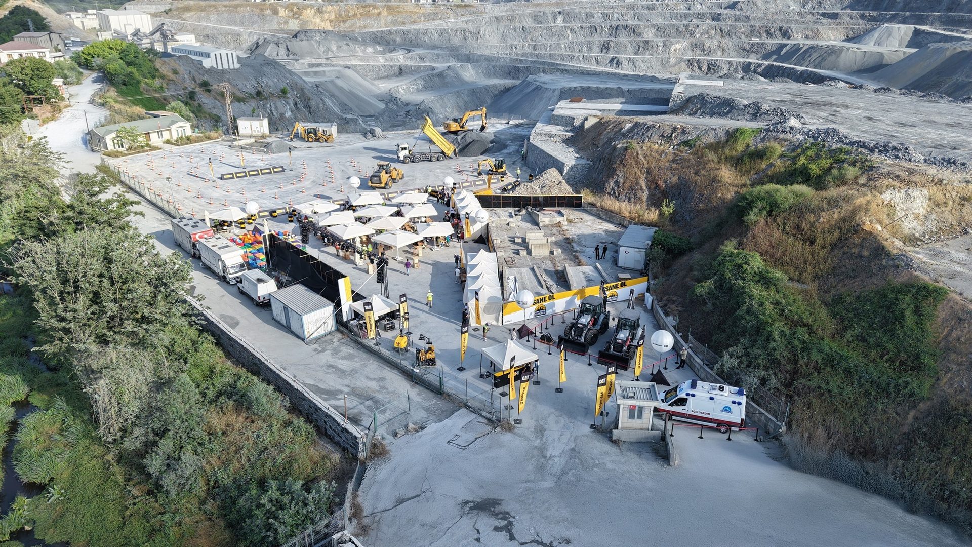 Outdoor event with heavy machinery display at a large open-pit mine.