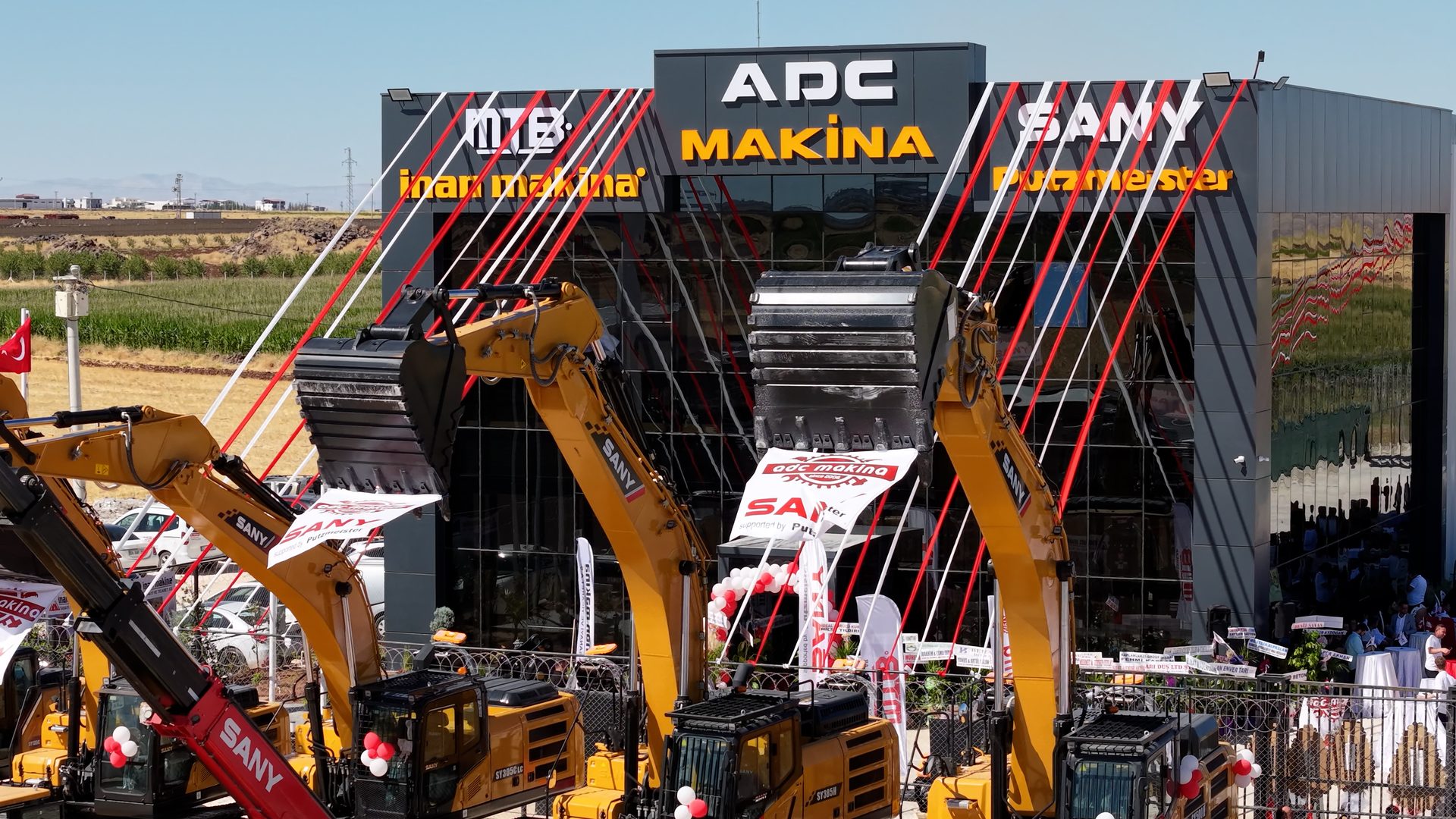 SANY excavators in front of ADC MAKINA building, decorated with red and white ribbons.