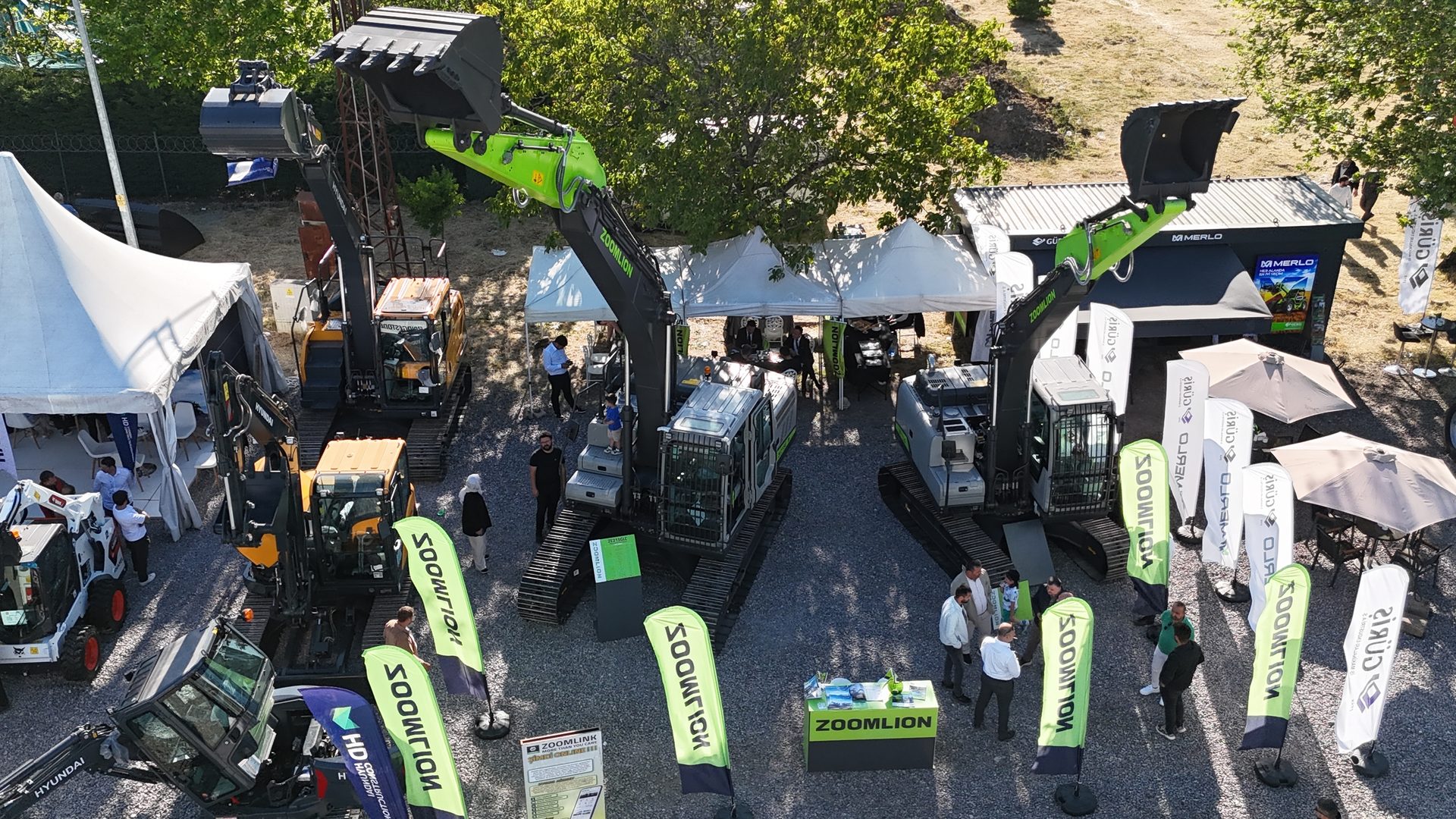 Aerial view of an outdoor exhibition featuring construction excavators and machinery from Zoomlion, Hyundai, and Merlo.