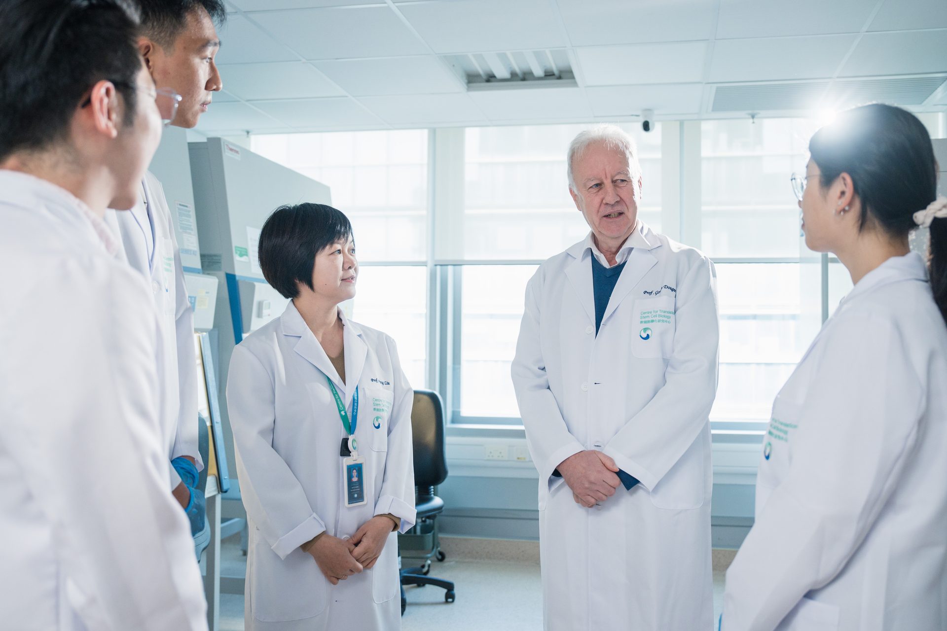 Scientists in lab coats discussing research in a bright laboratory, collaborating on scientific work.