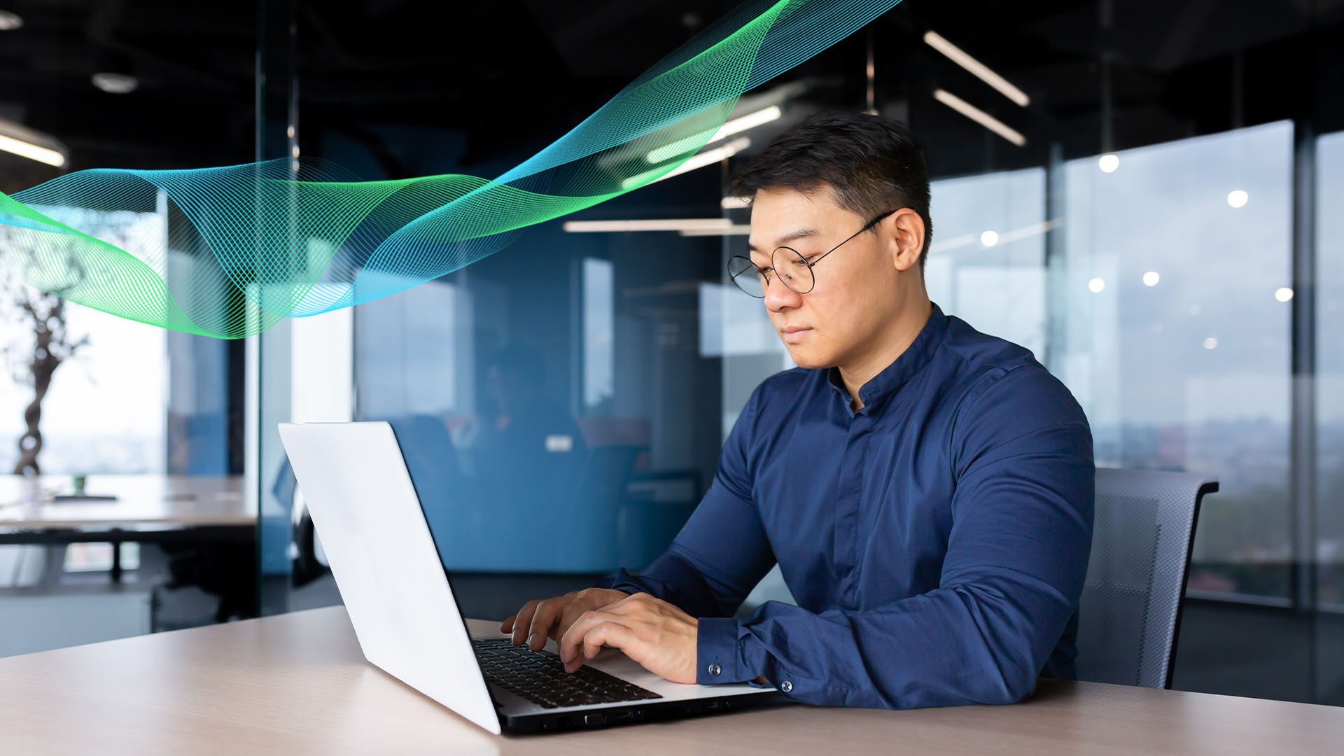 Asian man in glasses typing on laptop in a modern office with digital waves.