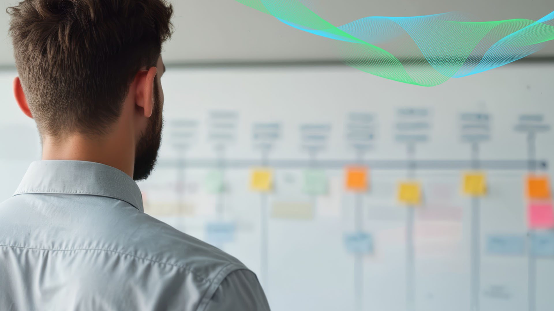 Man's back looking at a blurred whiteboard with colorful notes and abstract lines.