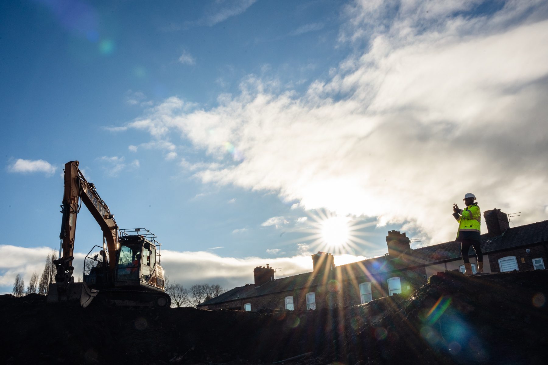 Sun shines over MSV construction site. Digger on the left and man in high vis vest on the right of the image