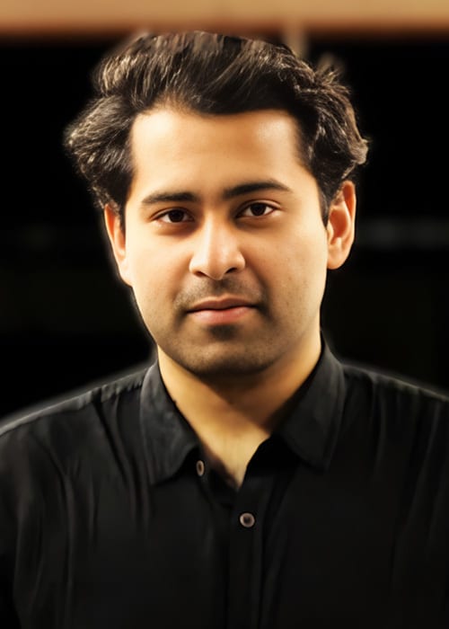 A man with dark hair and a dark shirt gazes directly at the viewer.