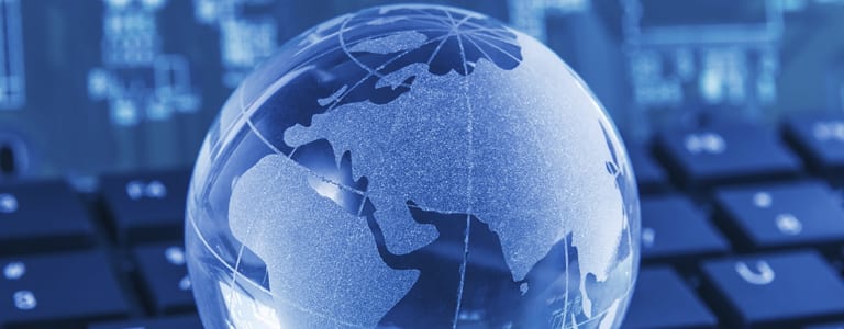 Blue glass globe with continents on a laptop keyboard.