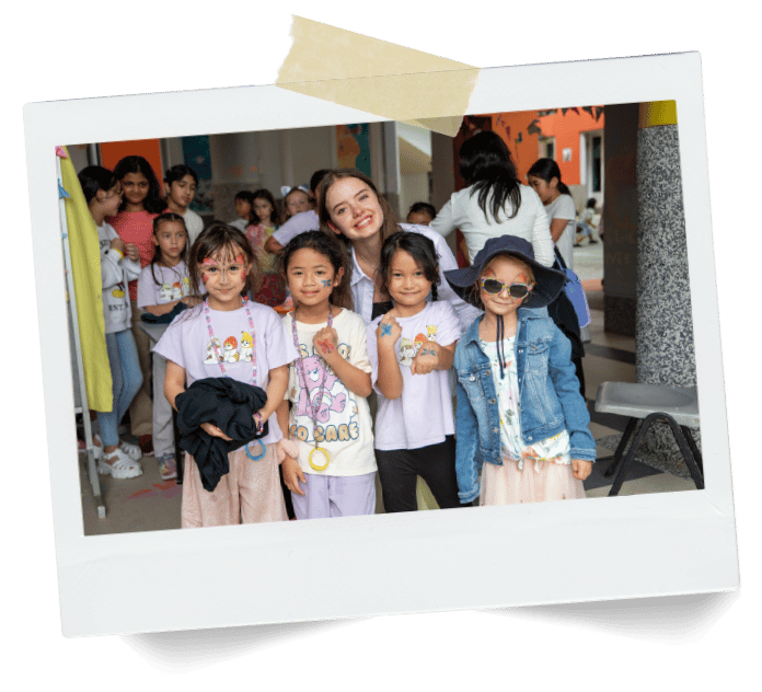 Smiling woman with four joyful girls, three with face paint.