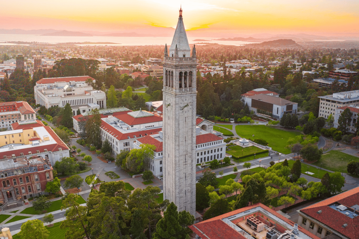 Aerial view of UC Berkeley's Campanile and campus at sunset, with the San Francisco Bay in the background.