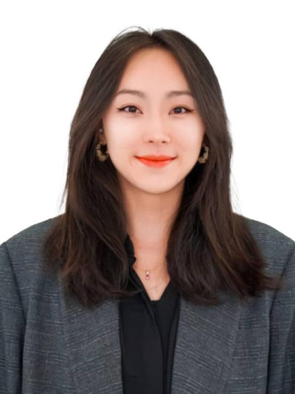 Smiling young Asian woman with long dark hair, wearing gray blazer, white background.