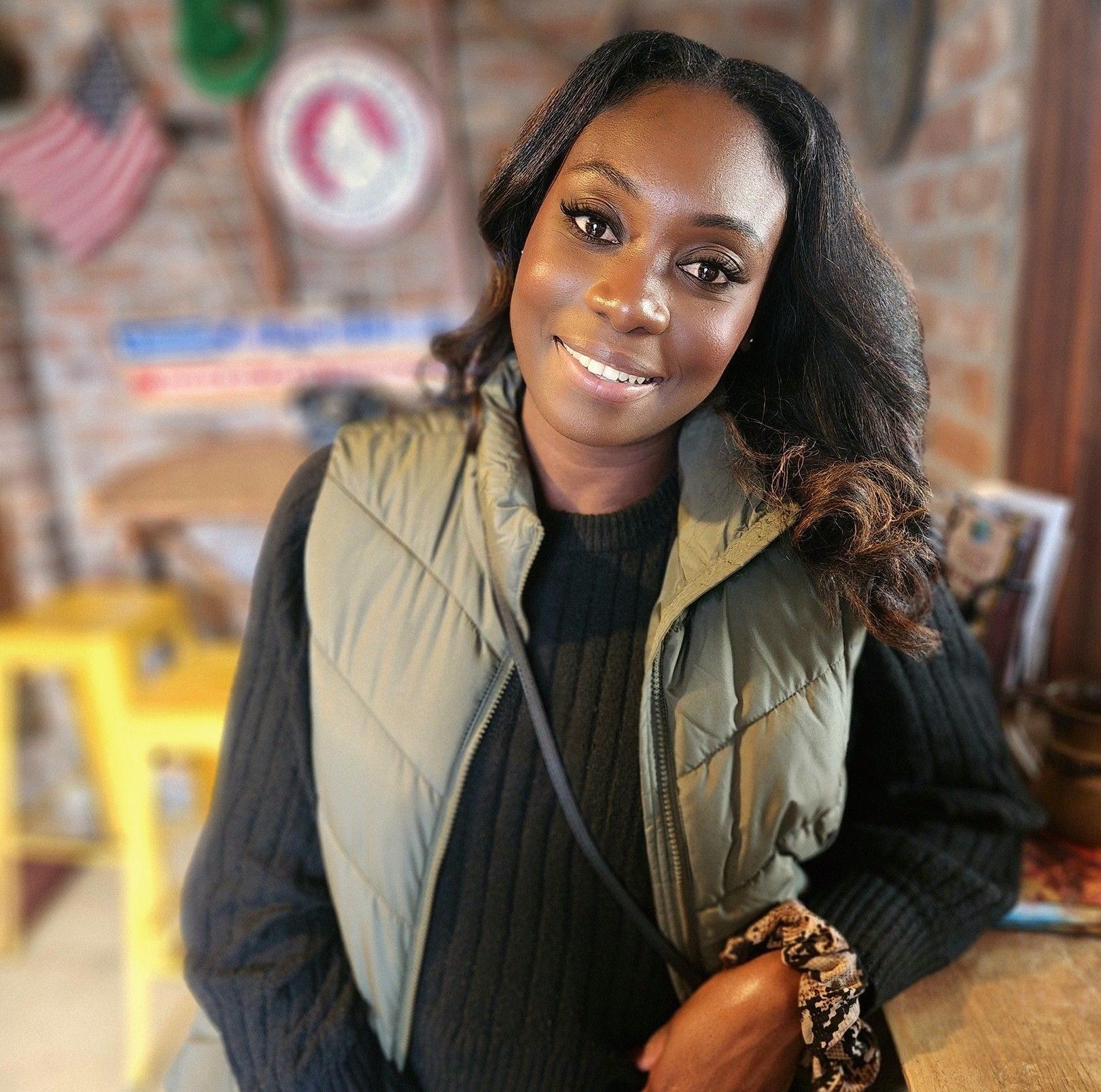 Smiling Black woman wearing a green vest.