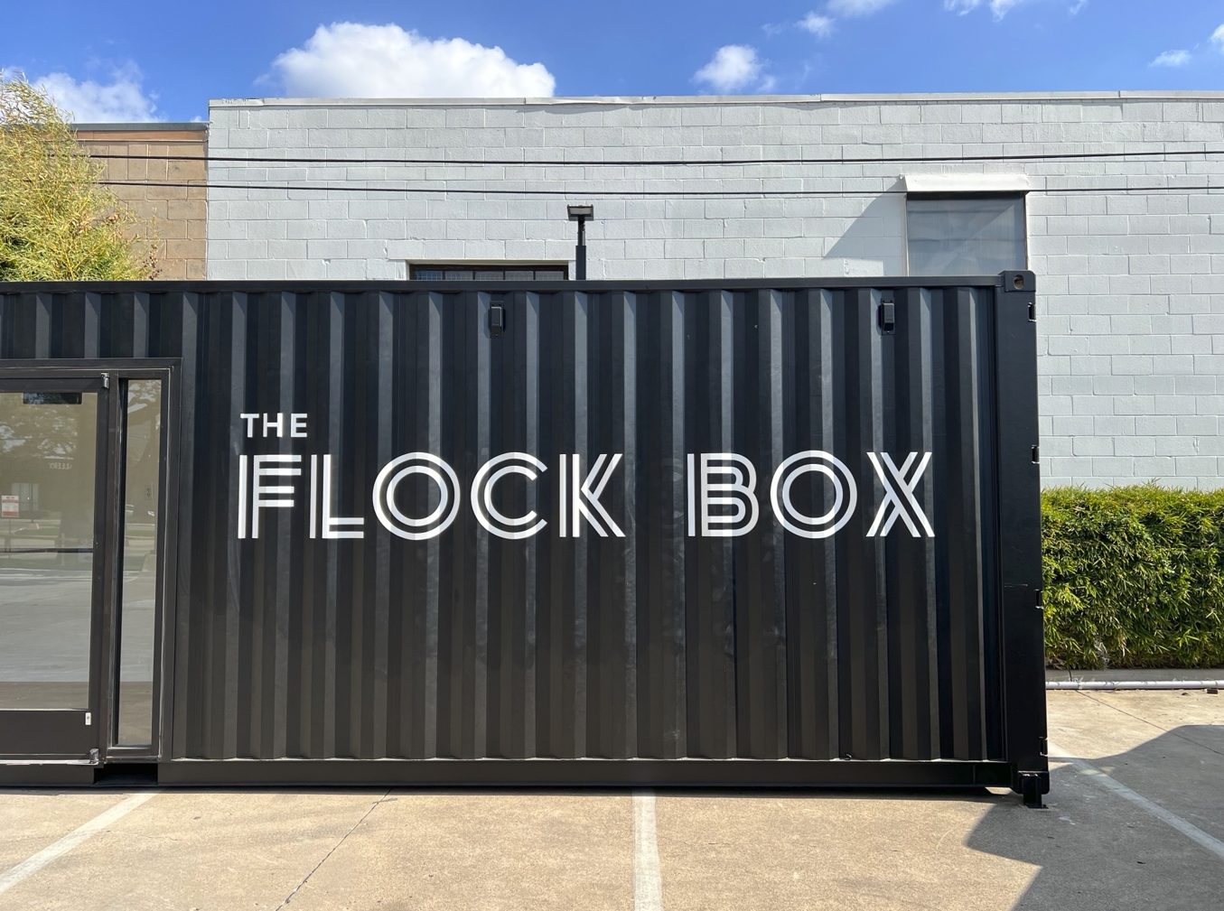 Black shipping container with white text: "THE FLOCK BOX".