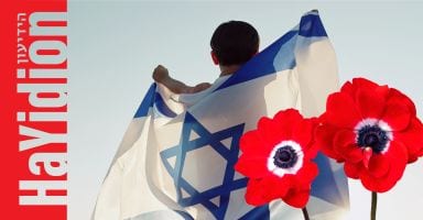 Child wrapped in Israeli flag, with two red flowers.