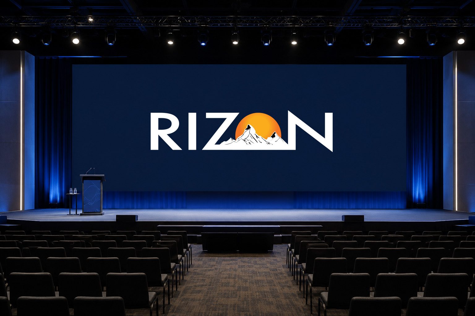 Empty auditorium with a stage and a large screen displaying the RIZON logo with mountains and a sun.