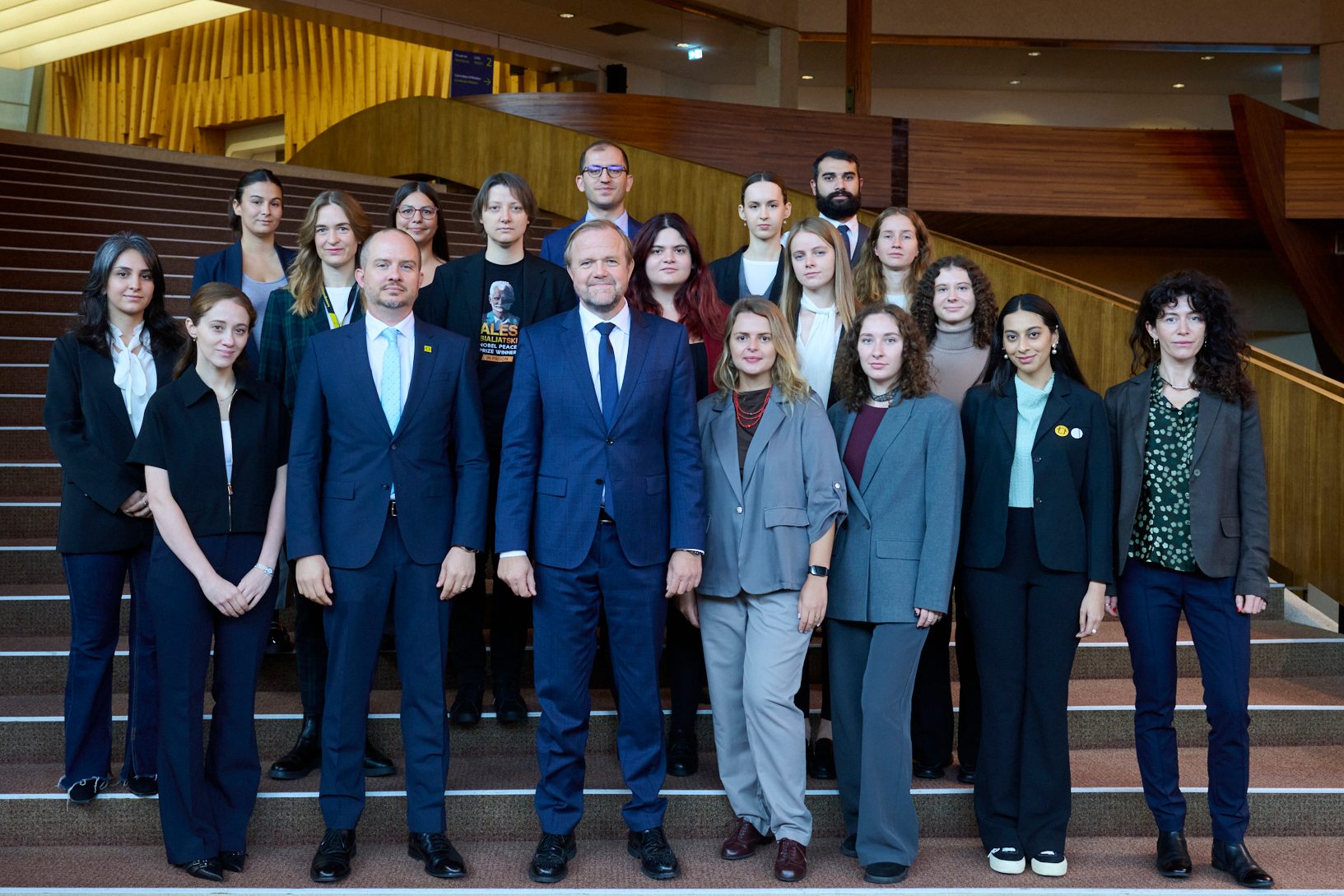 A large group of people, mostly young adults, in formal and business casual attire, standing on stairs.