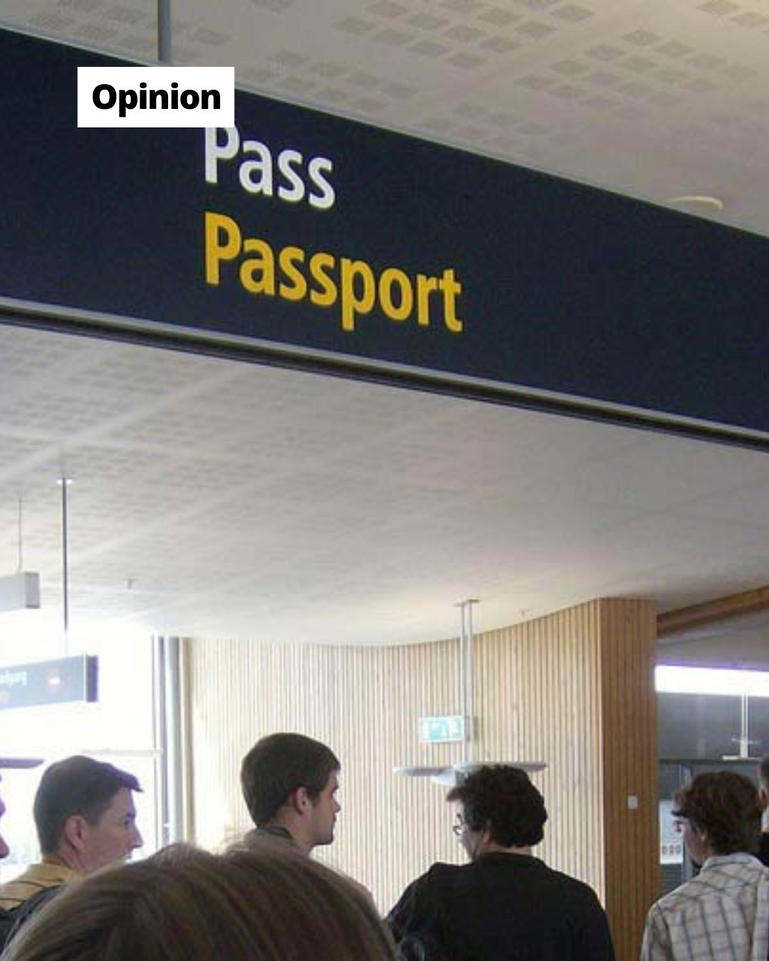 Travelers stand below a 'Pass Passport' sign at an airport, likely waiting in line for immigration.