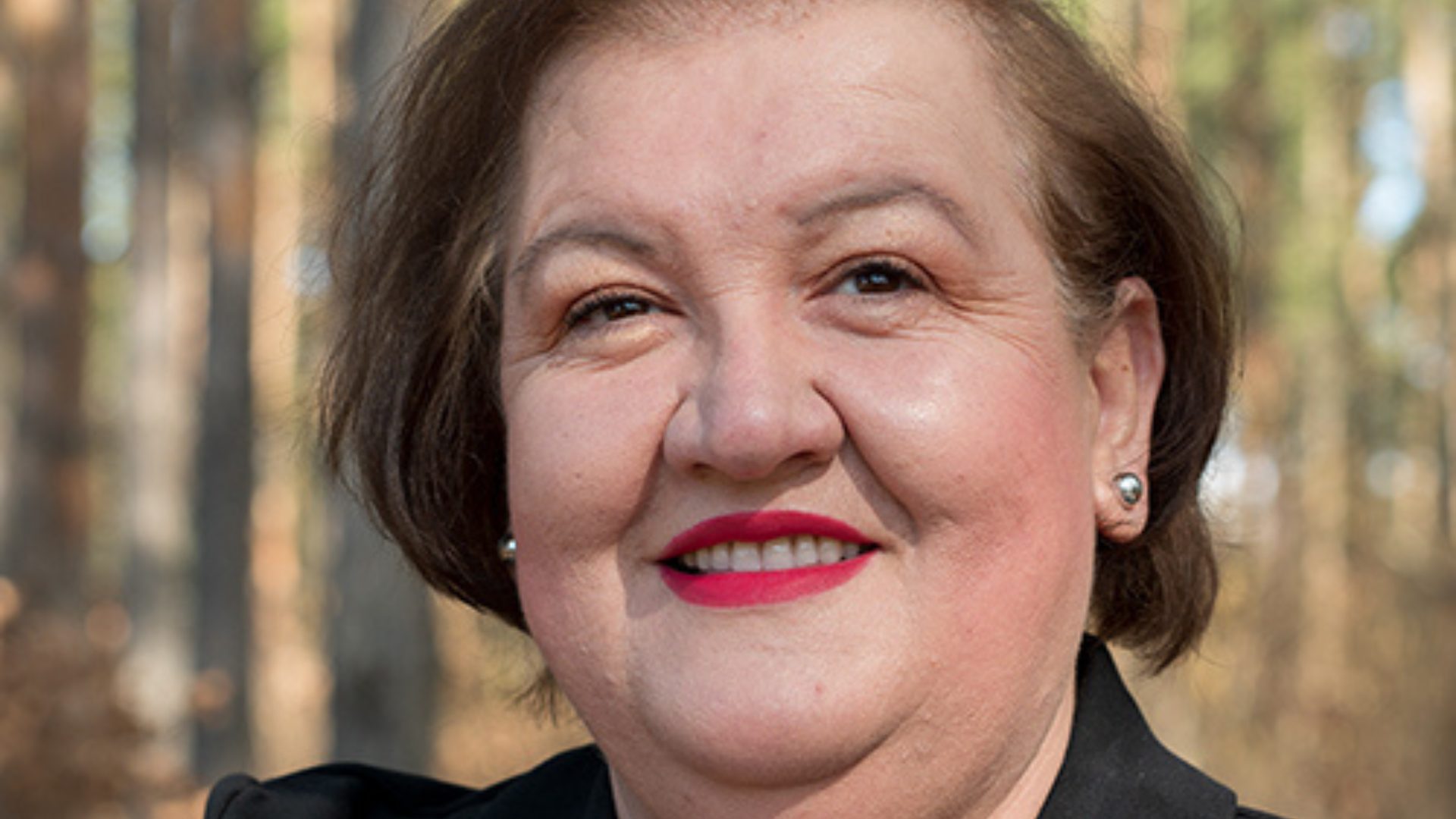 Smiling woman with dark hair and red lipstick.