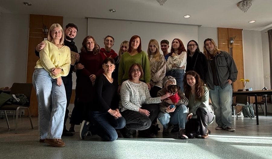 A diverse group of people and a small dog posing together for a photo in an indoor setting.