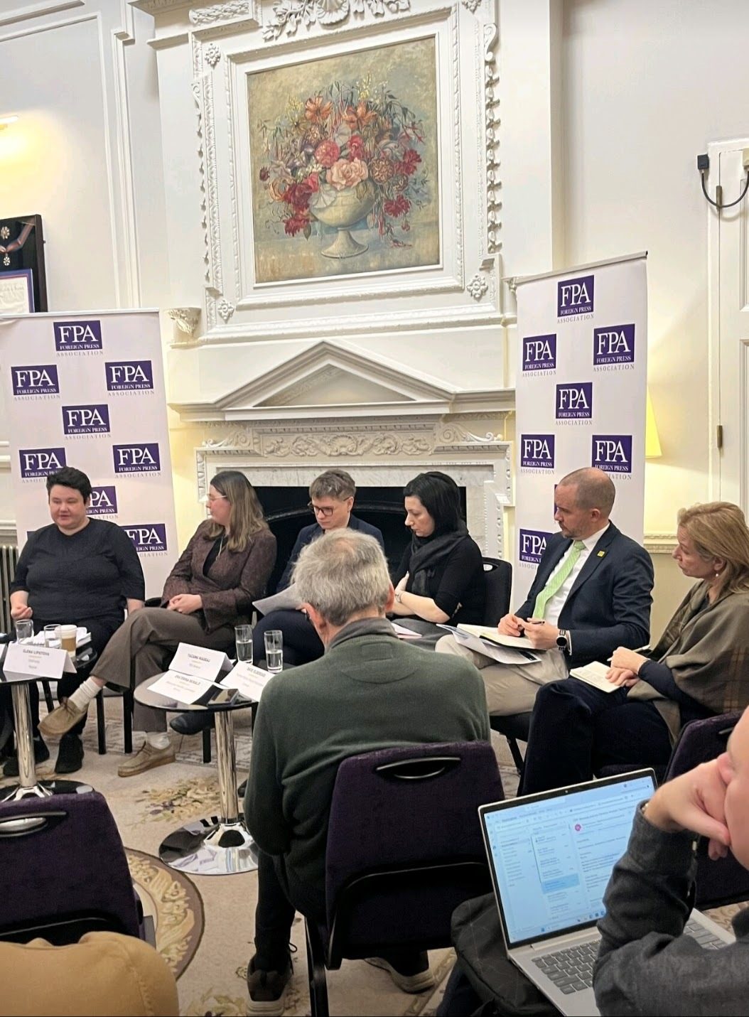 A group of people at a panel discussion with "Foreign Press Association" banners in the background.