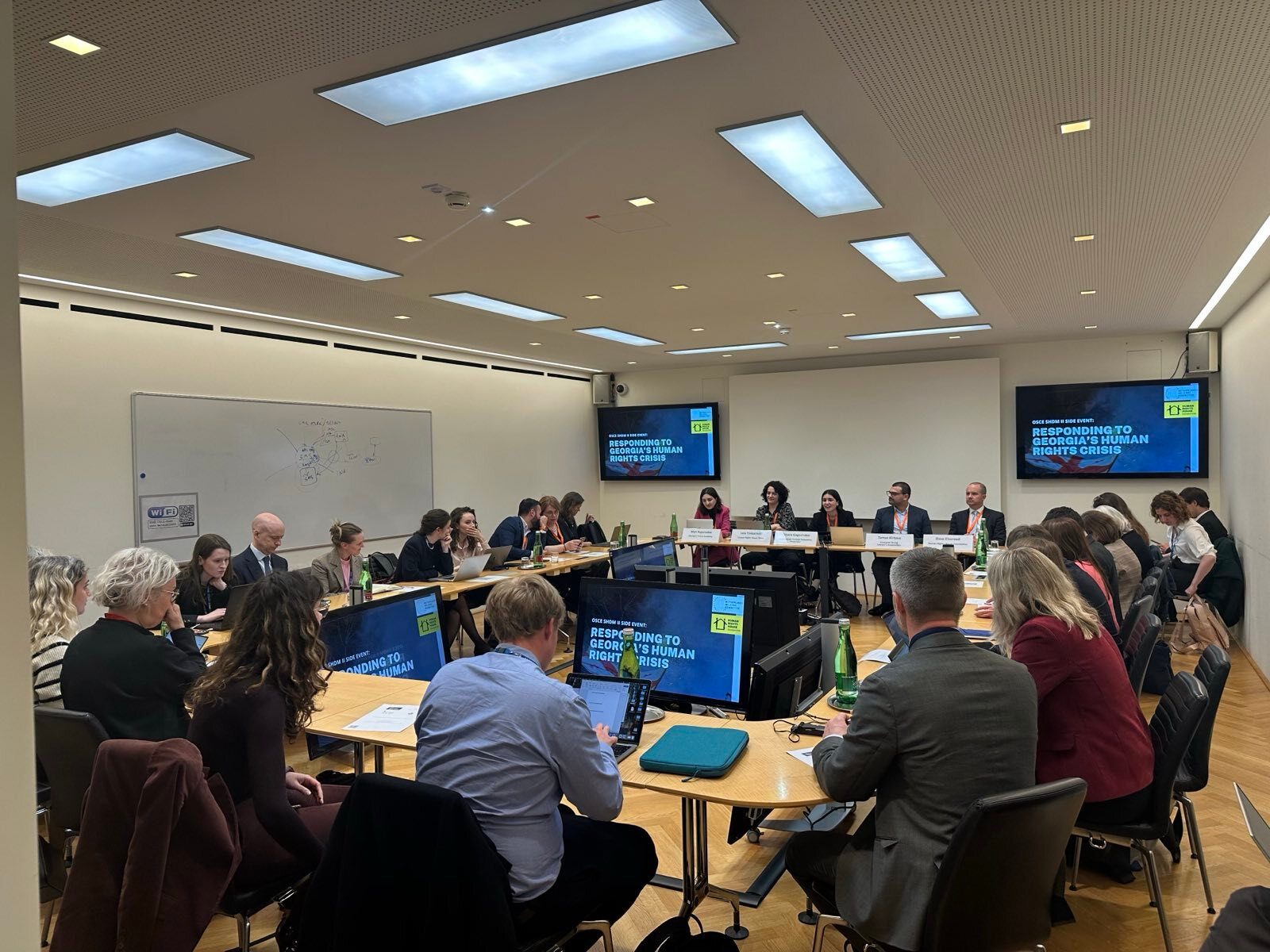A conference room with panelists and attendees for an event titled "Responding to Georgia's Human Rights Crisis."