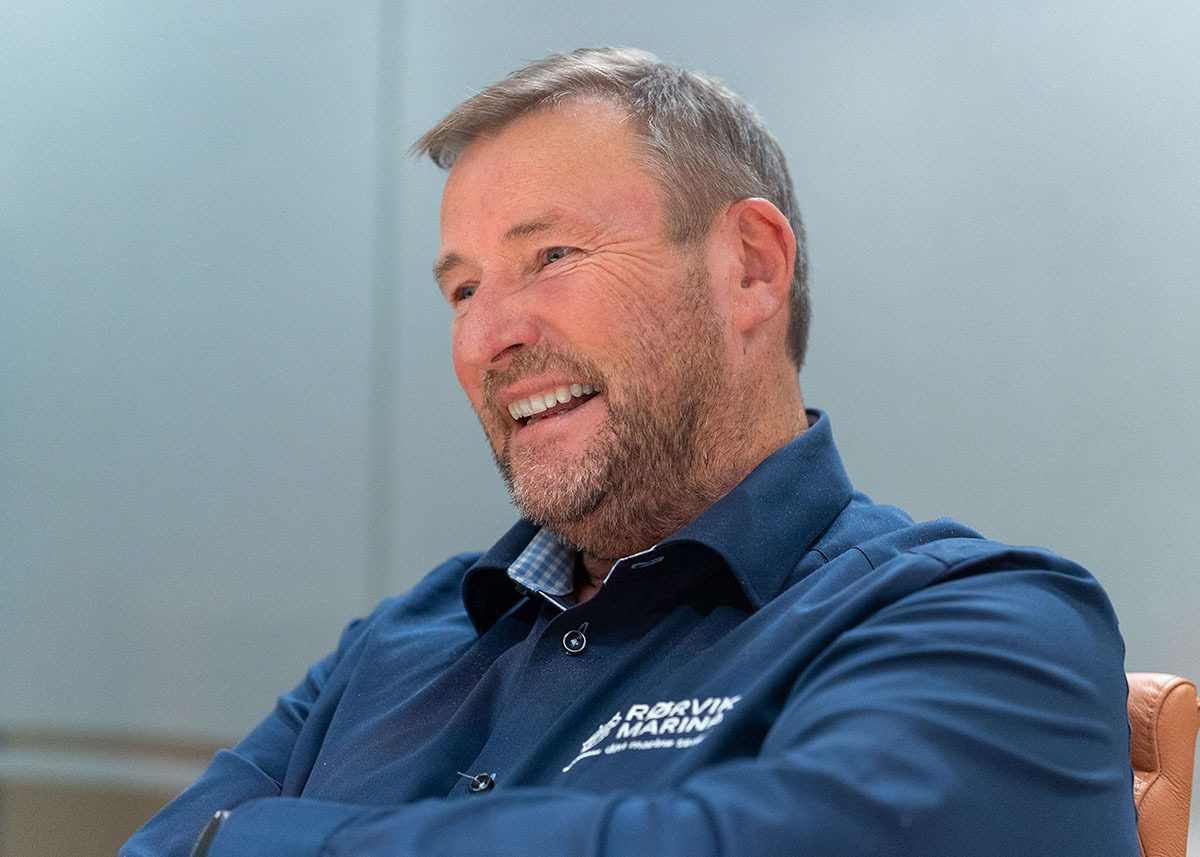 Smiling man with a beard in a blue shirt featuring a 'Rørvik Marina' logo.