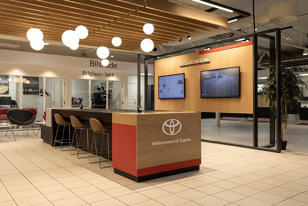 Modern Toyota showroom with a welcome desk, digital displays, and seating areas.