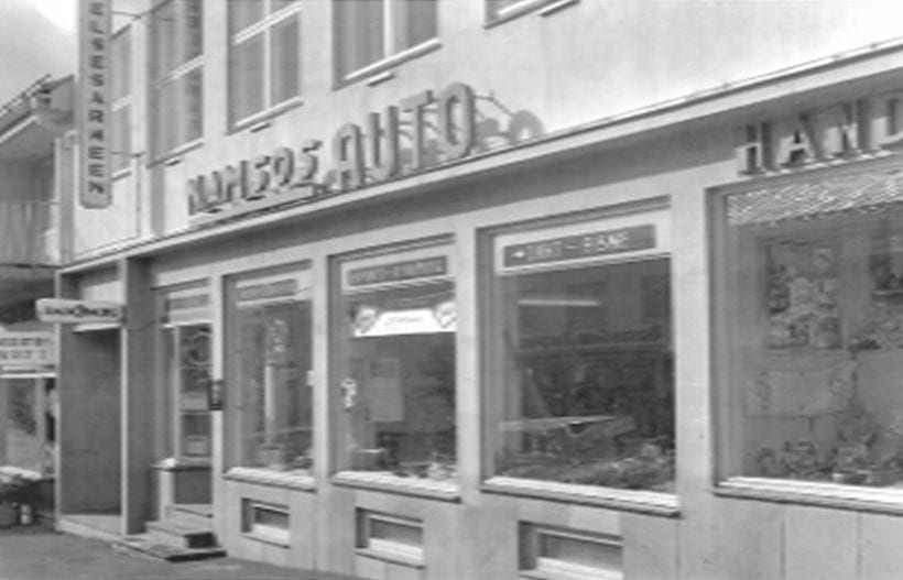 Vintage B&W storefront with "ELSESARKEN" and "KAESERS AUTO" signs.