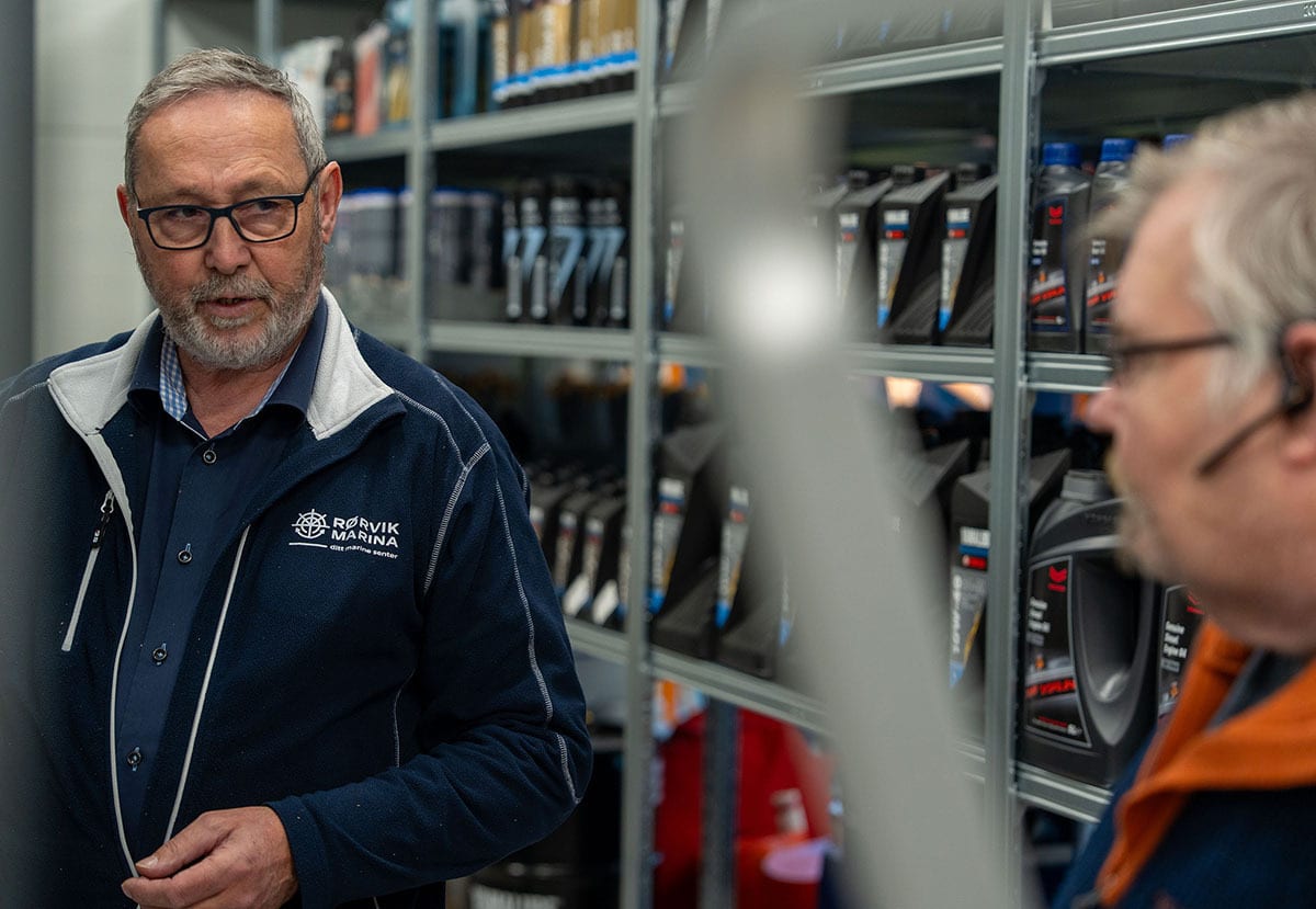 Man with glasses and beard in Rorvik Marina jacket talking, shelves of products in background.