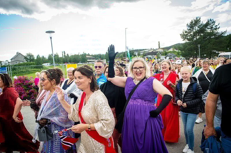 People in festive parade costumes waving.
