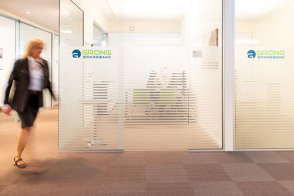 Blurred person passes frosted glass doors of Grong Sparebank office.