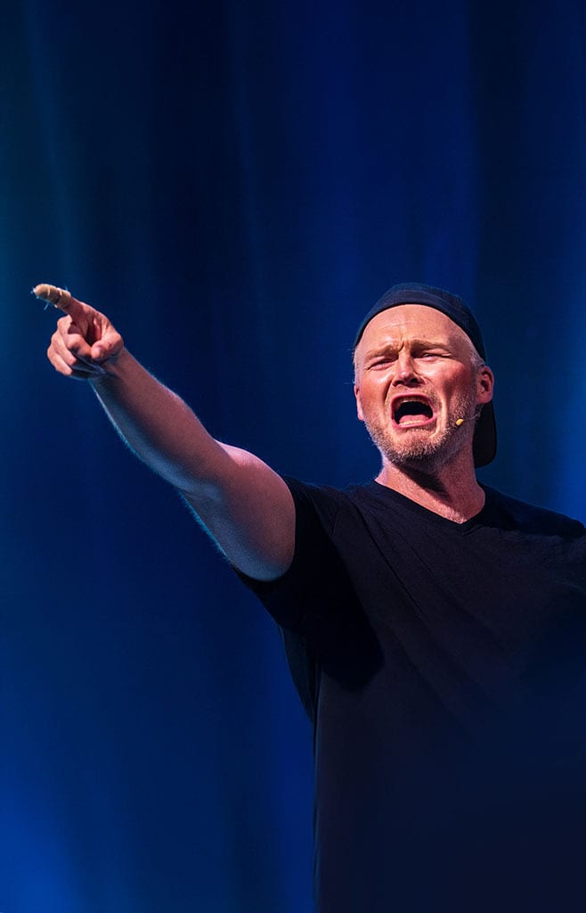 Man in black cap pointing and yelling with open mouth.