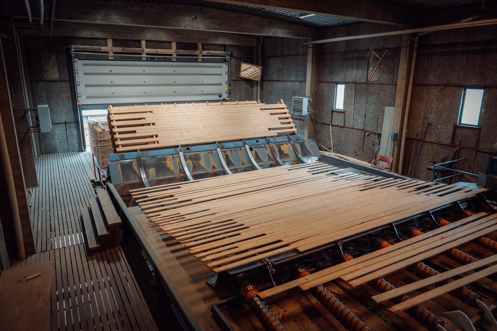 Industrial wood drying facility with stacks of timber planks on automated machinery.