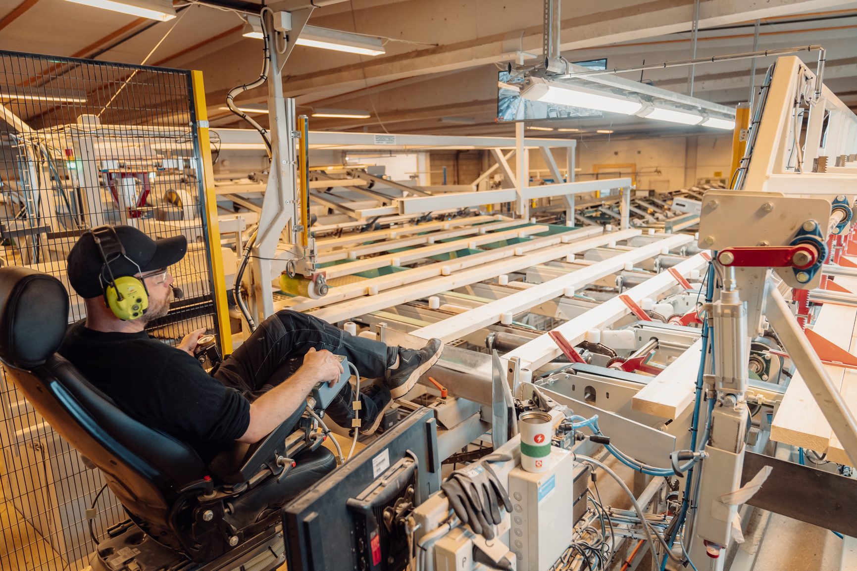 Man in ear protection operates industrial wood processing machinery.