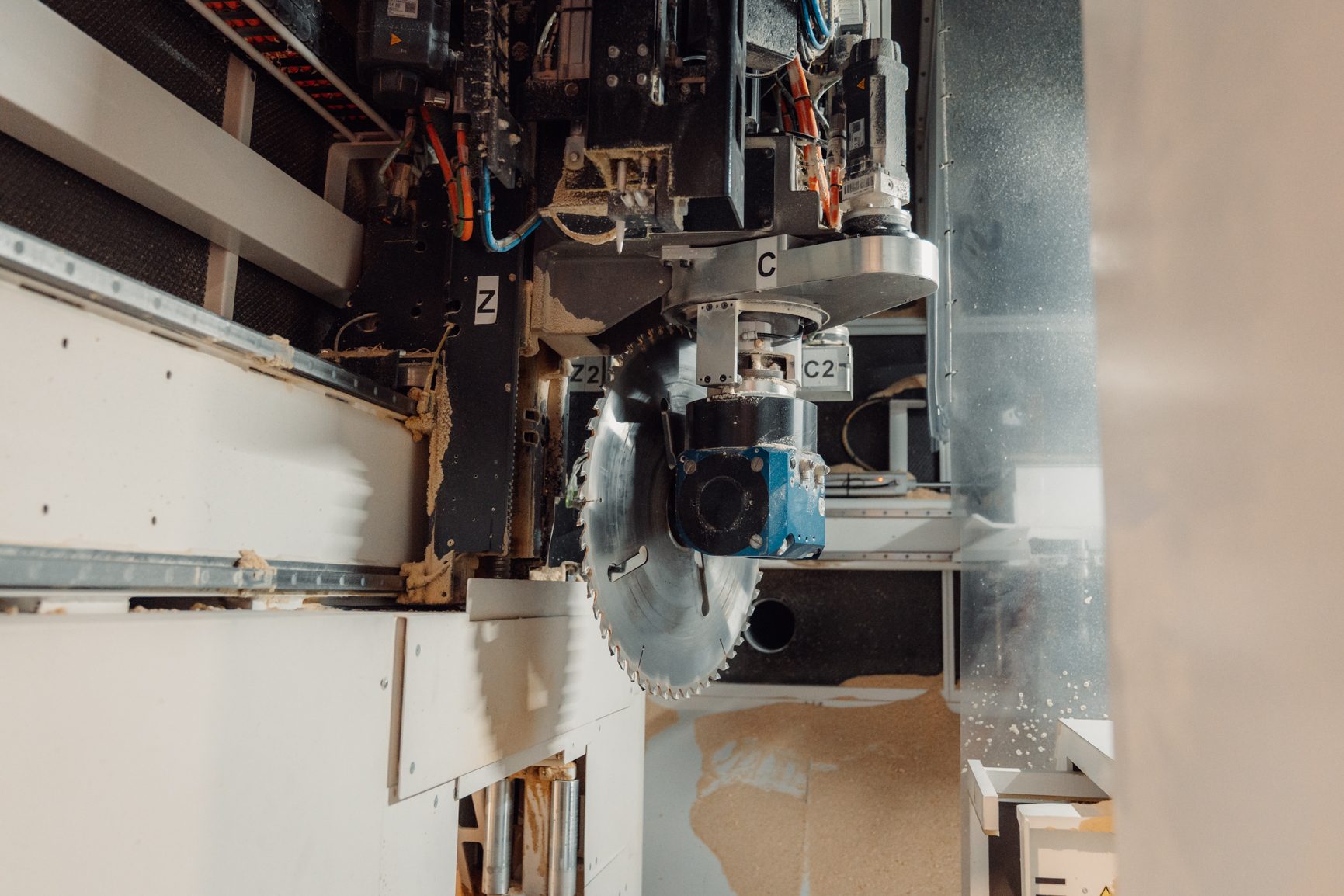 Industrial CNC woodcutting machine with a circular saw blade and sawdust.