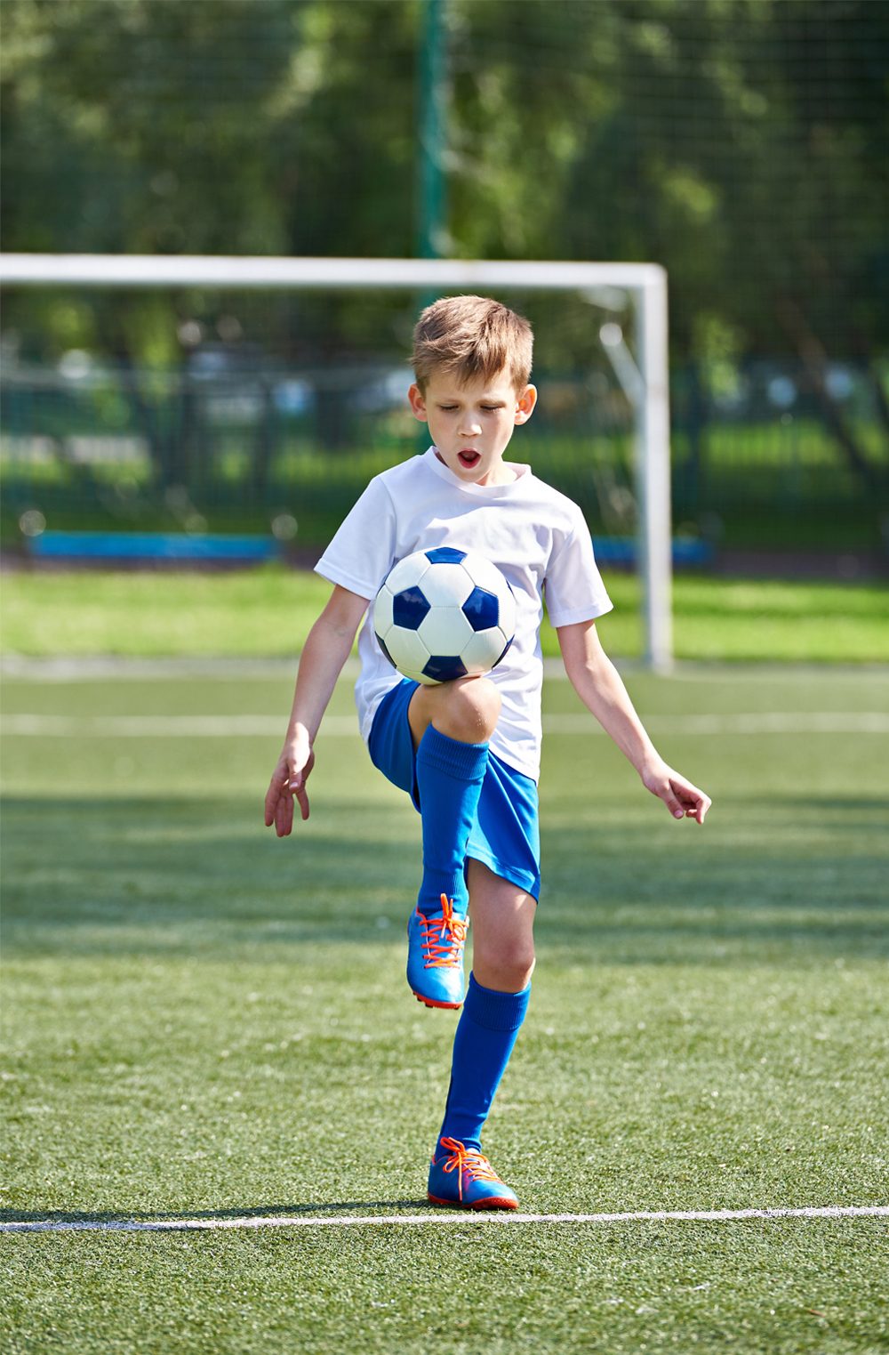 Boy on a football pitch kicking a ball