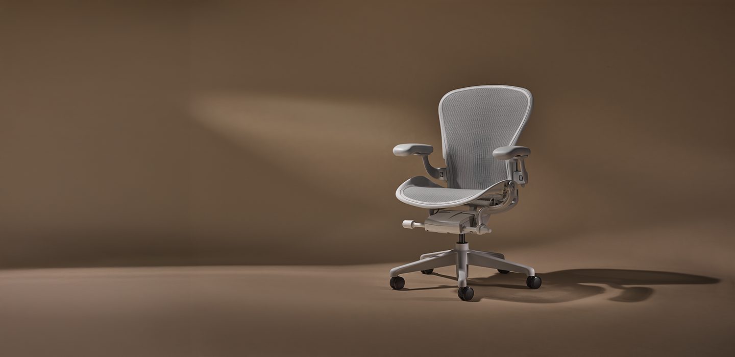 Light gray mesh office chair on a brown background.