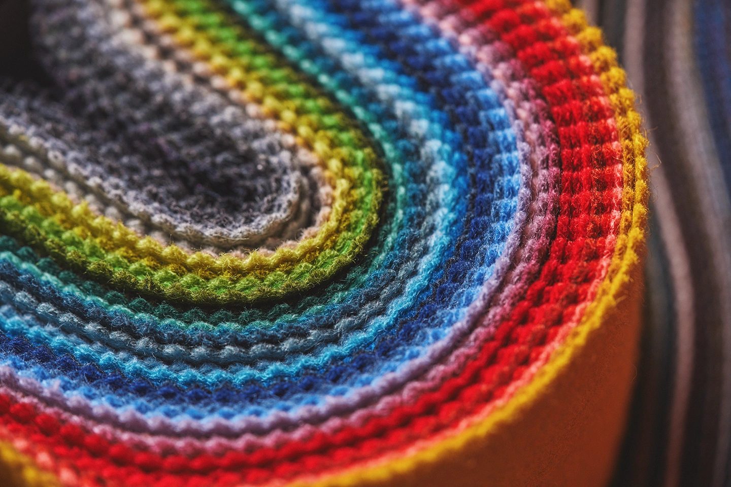 Close-up of a vibrant rainbow-colored fabric roll, showing its layered texture.