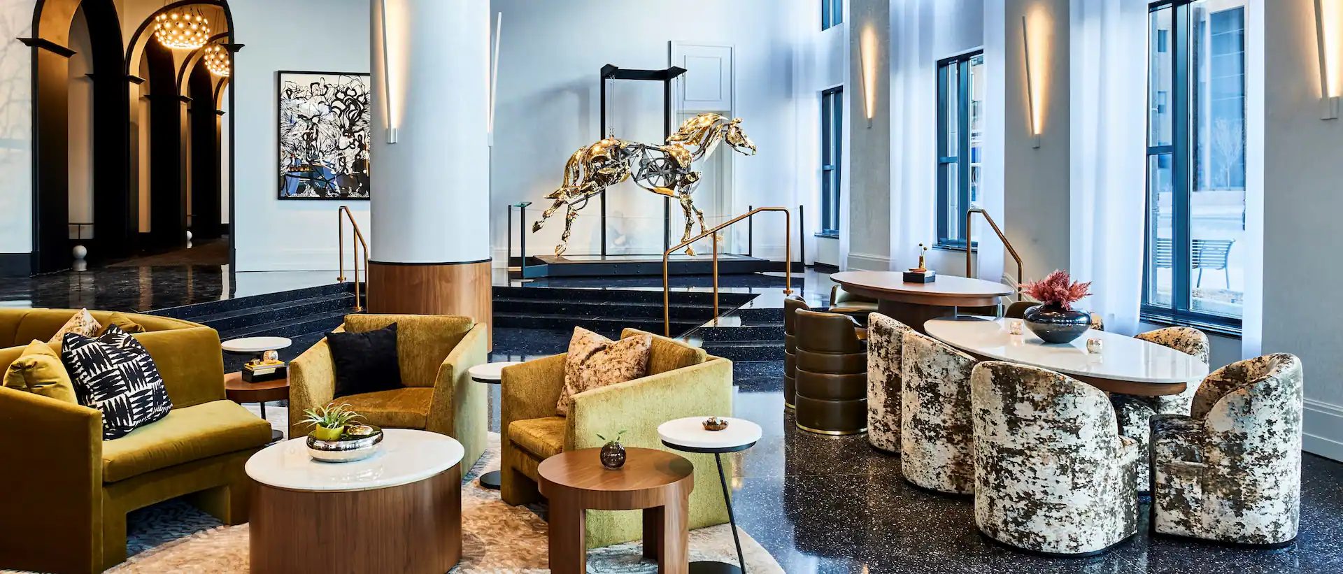 Luxurious lobby with a gold horse sculpture, velvet lounge seating, and an arched entrance.
