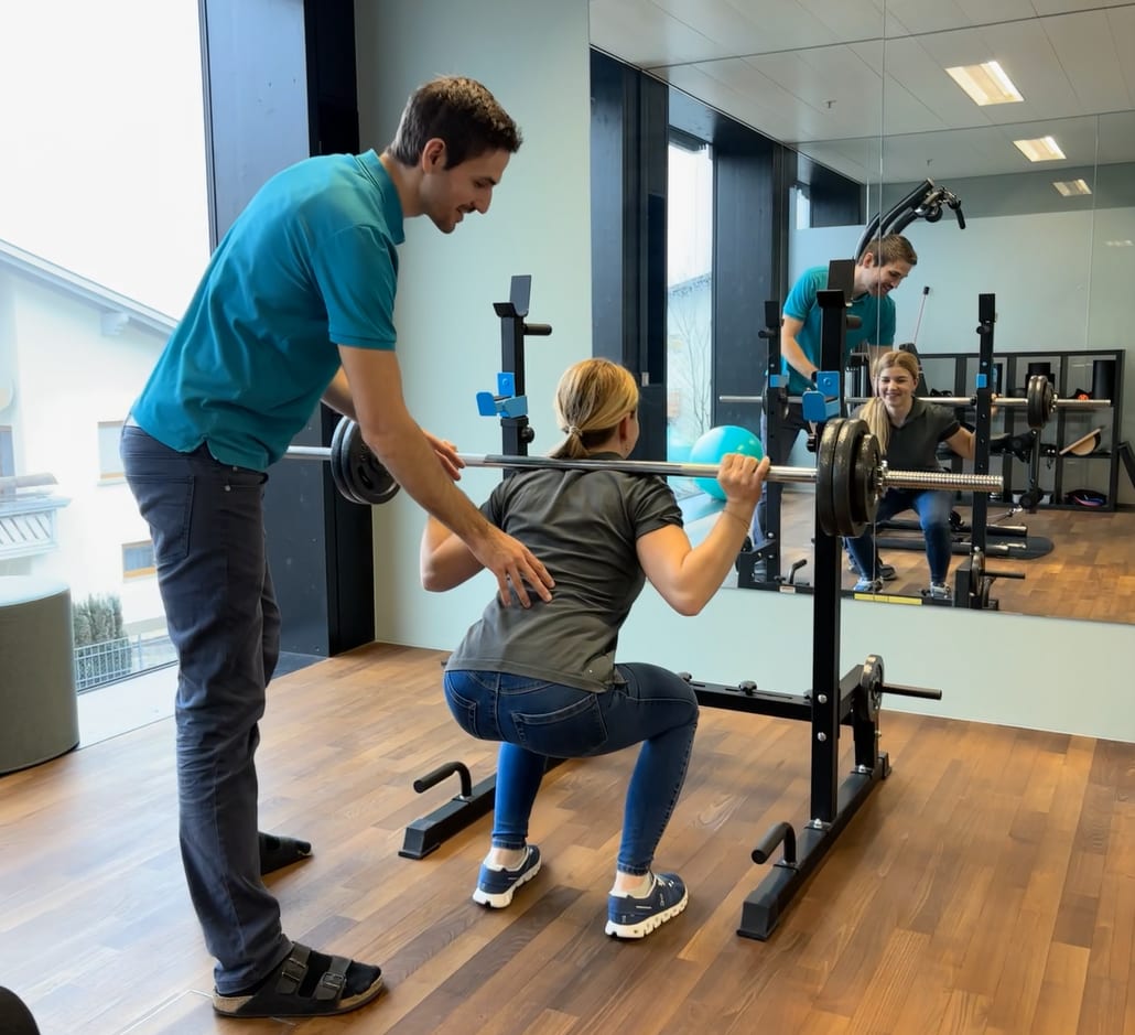 Trainer guides woman doing barbell squats, both smiling in mirror.