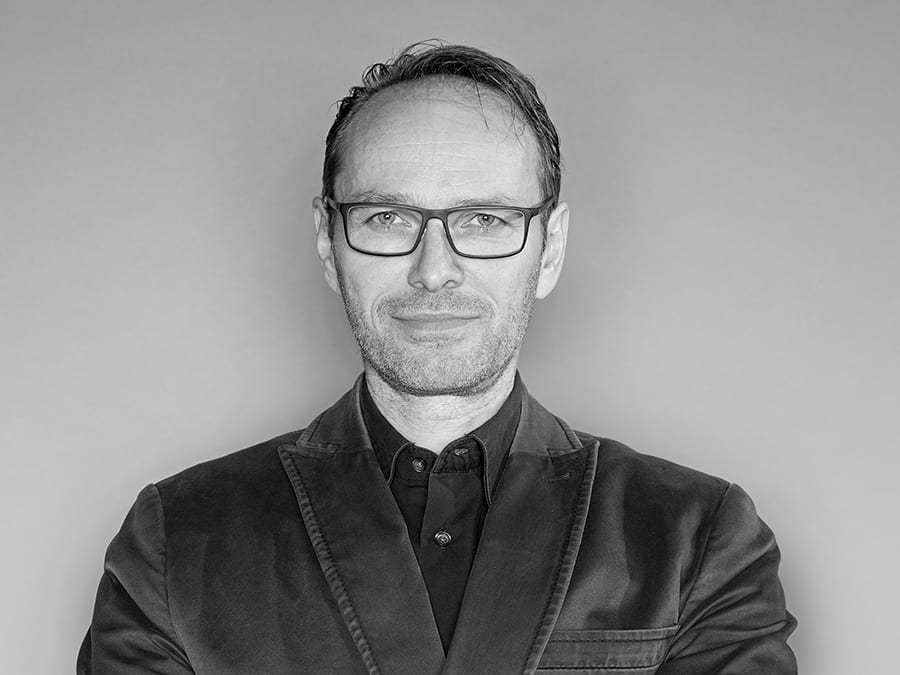 Black and white portrait of a man in glasses and a jacket.