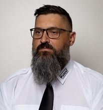 Bearded man in glasses, white shirt, and black tie.
