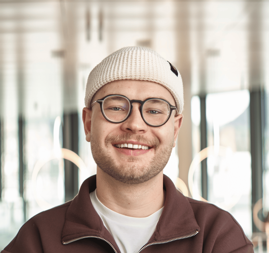 Smiling man in a white beanie and glasses, looking directly at the camera.