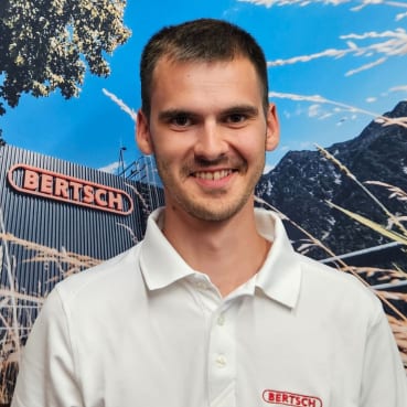 Smiling man in white BERTSCH polo shirt, with BERTSCH sign in background.