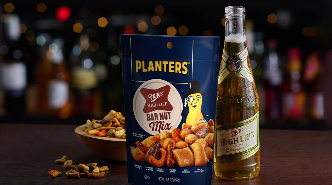 Pouch of Planters Miller High Life nut mix next to bottle of beer