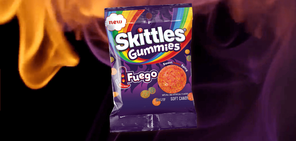 Skittles Gummies Fuego candy bag against a fiery background.