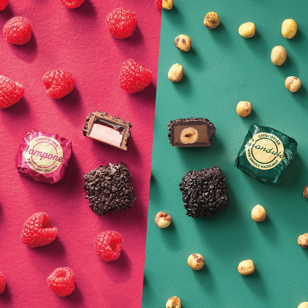 Raspberry chocolates and berries on red; hazelnut chocolates and nuts on green, some open.