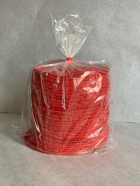 A tall stack of red tortillas packaged in a clear plastic bag, tied at the top.