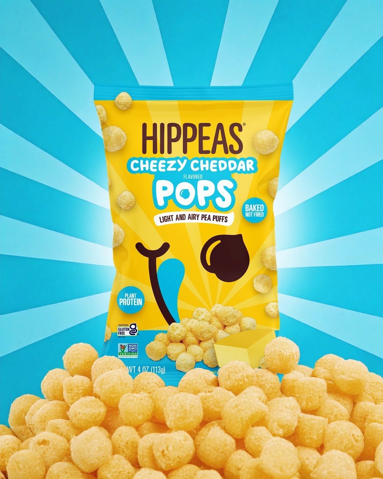 Yellow Hippeas Cheezy Cheddar Pops bag surrounded by pea puffs on blue ray background.