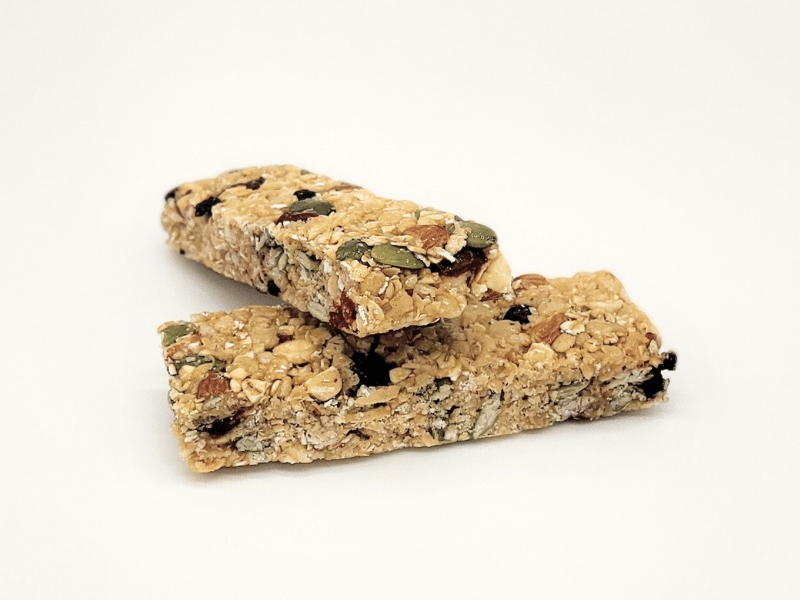 Two granola bars with nuts, seeds, and dried fruit on a white background.