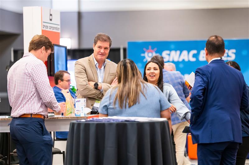 Conference attendees networking and conversing at an event booth.