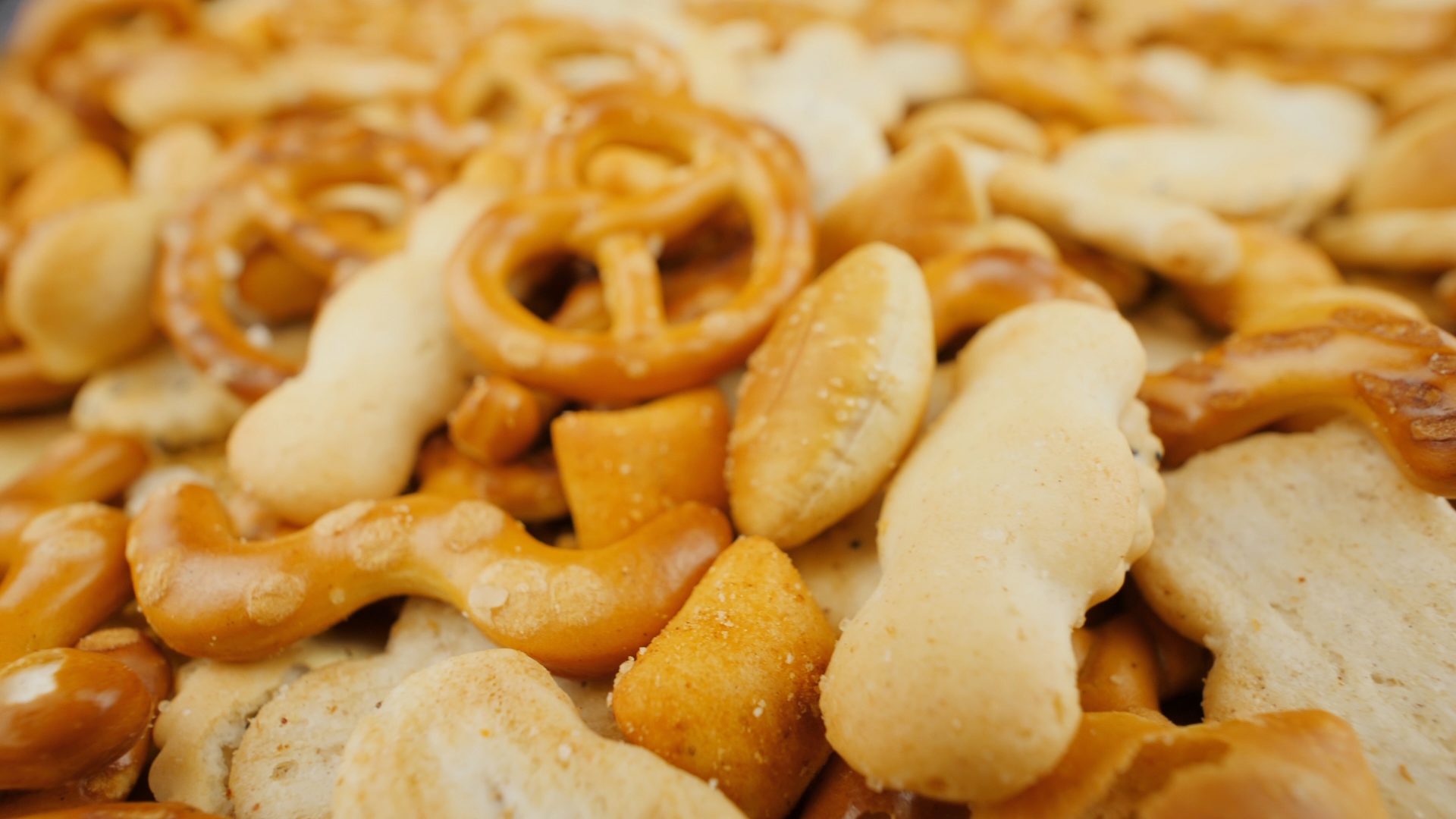 Pile of assorted pretzels and crackers in various golden-brown shapes.